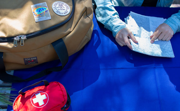 A Large Shepherd's Wool Utility Cloth in Neela Blue being used as a table cloth at a picnic table with a person holding a map on top of it.